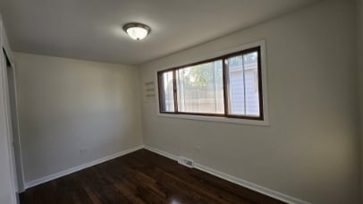 unfurnished bedroom with dark wood-style floors, a closet, visible vents, and baseboards