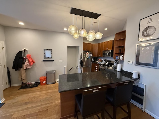 kitchen with light wood-type flooring, appliances with stainless steel finishes, a peninsula, brown cabinetry, and open shelves