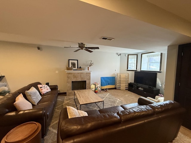 carpeted living room featuring a tiled fireplace, a ceiling fan, and visible vents