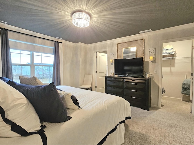 bedroom with baseboards, a walk in closet, visible vents, and light colored carpet