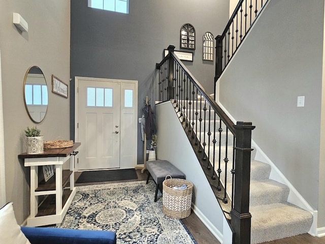 foyer featuring a wealth of natural light, a towering ceiling, and wood finished floors