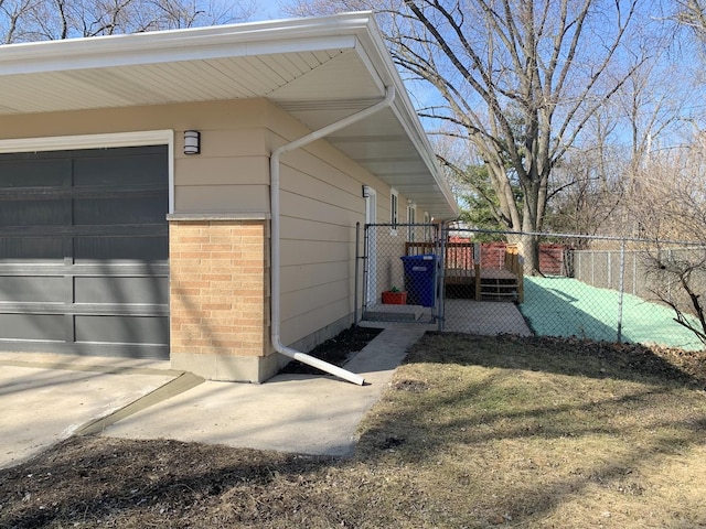 property entrance featuring brick siding, a gate, a garage, and fence