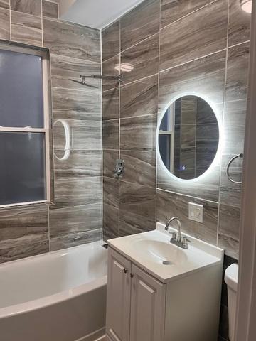 full bath featuring tasteful backsplash, bathing tub / shower combination, toilet, vanity, and tile walls