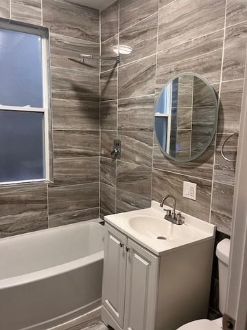 bathroom with shower / bathtub combination, toilet, vanity, tile walls, and backsplash