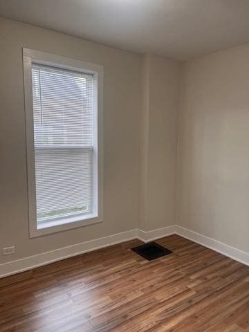 spare room featuring visible vents, baseboards, and wood finished floors