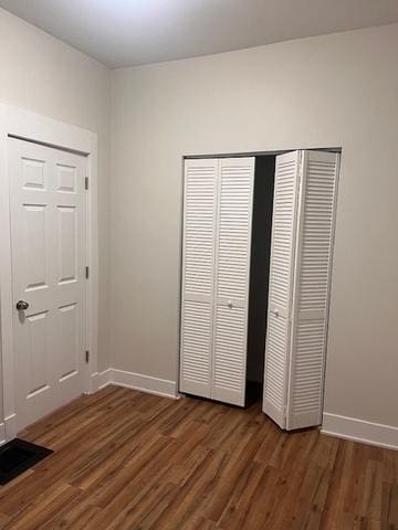 unfurnished bedroom featuring a closet, wood finished floors, visible vents, and baseboards