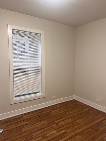 unfurnished room featuring dark wood-style floors and baseboards