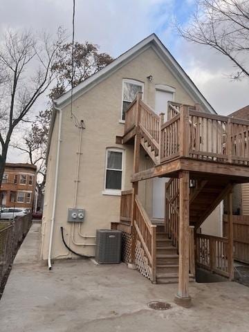 rear view of property featuring a deck, central air condition unit, fence, stairway, and a patio area