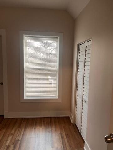 unfurnished bedroom with vaulted ceiling, wood finished floors, and baseboards