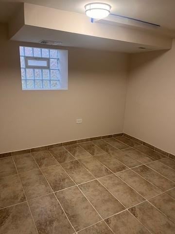 basement featuring dark tile patterned floors and baseboards