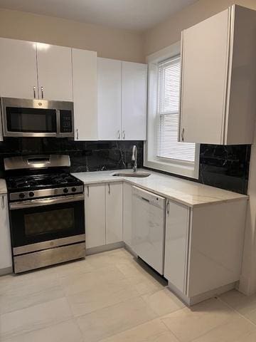 kitchen with stainless steel appliances, a sink, light countertops, and white cabinets