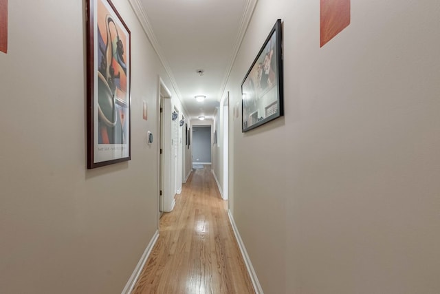 hallway featuring light wood-type flooring, baseboards, and crown molding