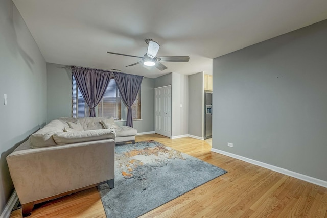 living area featuring light wood-type flooring, ceiling fan, and baseboards