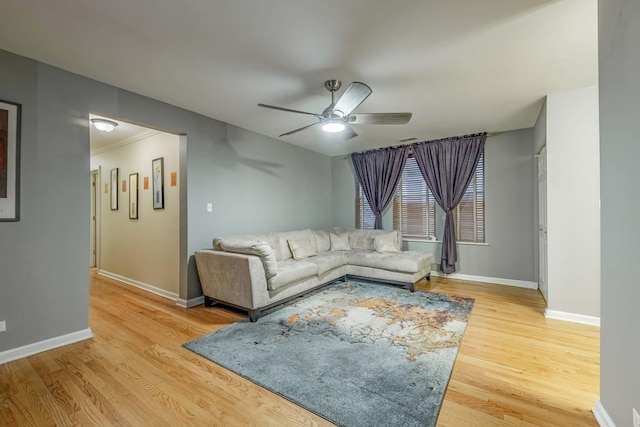 living area featuring baseboards, a ceiling fan, and light wood-style floors