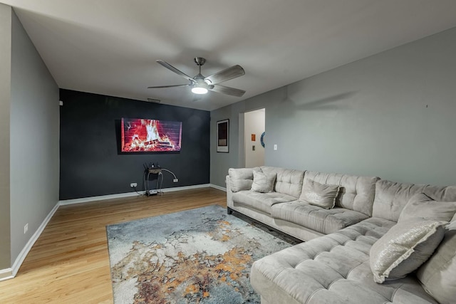 living area with a ceiling fan, baseboards, and wood finished floors