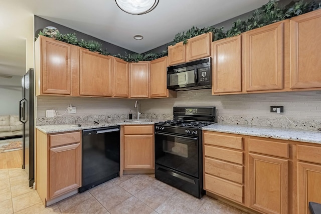 kitchen with black appliances, a sink, and light brown cabinetry