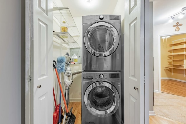 laundry area with stacked washer and dryer, laundry area, and light wood finished floors