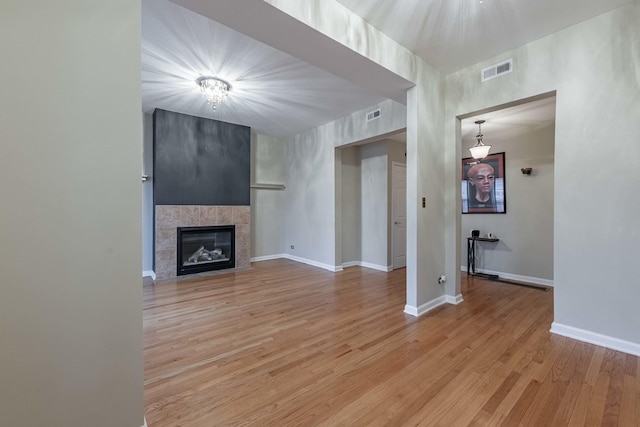 unfurnished living room featuring light wood-style floors, visible vents, a fireplace, and baseboards