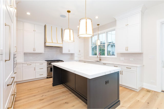 kitchen featuring light wood-style floors, high end stainless steel range, white cabinets, and custom range hood