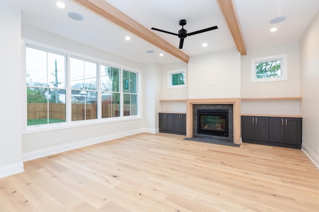 unfurnished living room featuring recessed lighting, a fireplace with flush hearth, light wood-style floors, baseboards, and beam ceiling