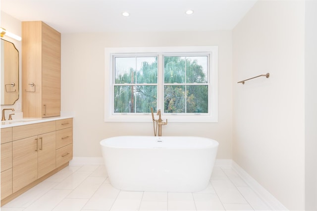 full bathroom with baseboards, tile patterned floors, vanity, a freestanding tub, and recessed lighting