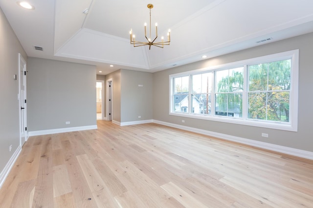 spare room featuring light wood-type flooring, visible vents, a notable chandelier, and baseboards