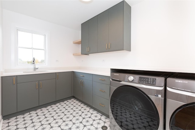 washroom with cabinet space, washer and dryer, light floors, and a sink