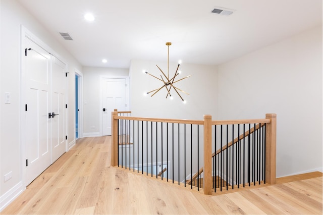 hall featuring recessed lighting, visible vents, an upstairs landing, and wood finished floors