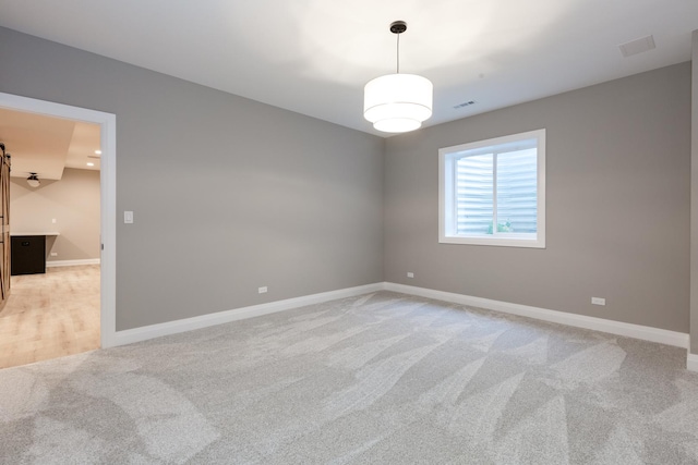 unfurnished room featuring light carpet, baseboards, and visible vents