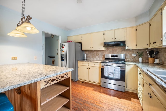 kitchen with backsplash, appliances with stainless steel finishes, cream cabinetry, and under cabinet range hood