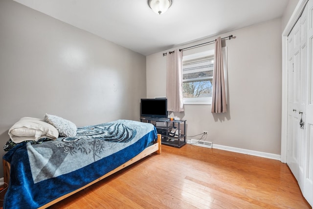 bedroom featuring visible vents, baseboards, light wood-style floors, and a closet