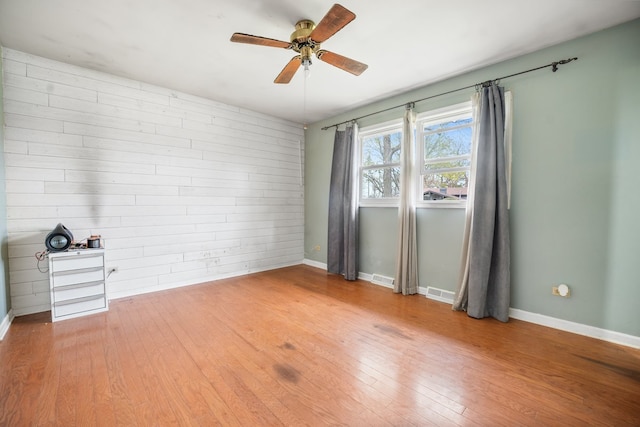 unfurnished room with baseboards, a ceiling fan, hardwood / wood-style floors, and visible vents