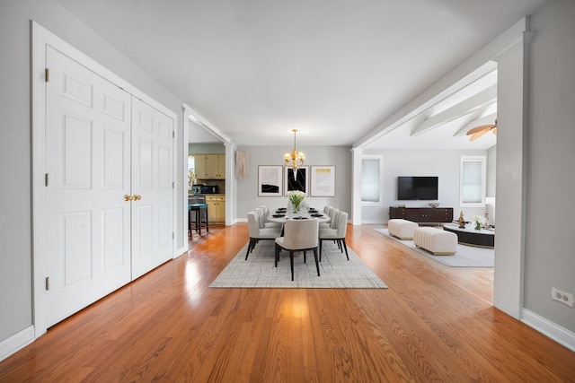 dining area with ceiling fan with notable chandelier, baseboards, and light wood-style floors