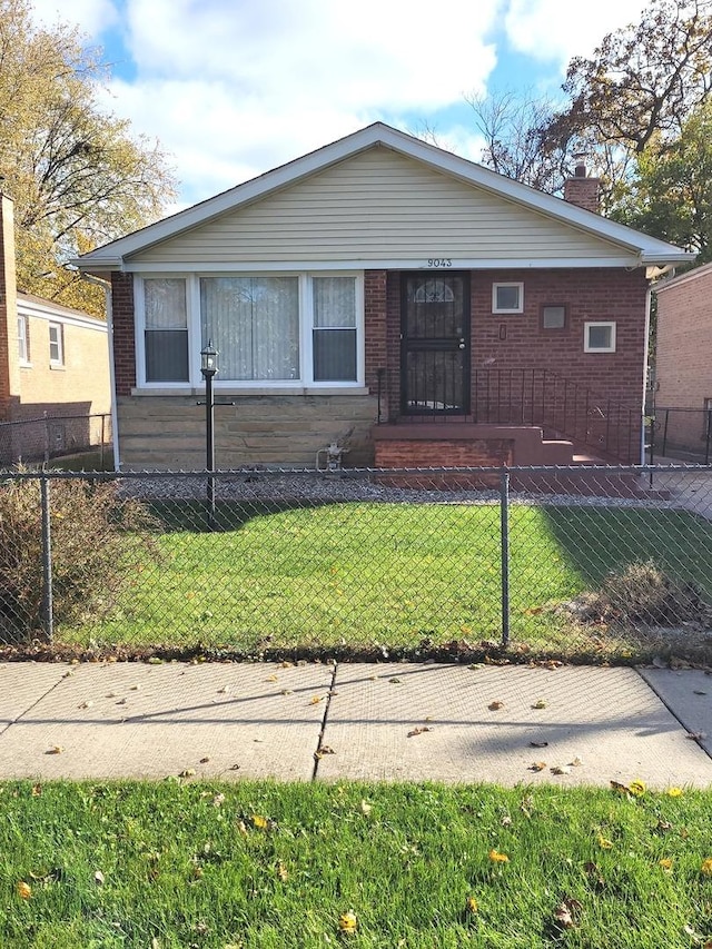 view of front of home with a fenced front yard, a front yard, and brick siding