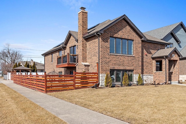 exterior space featuring a chimney, fence, a lawn, and brick siding