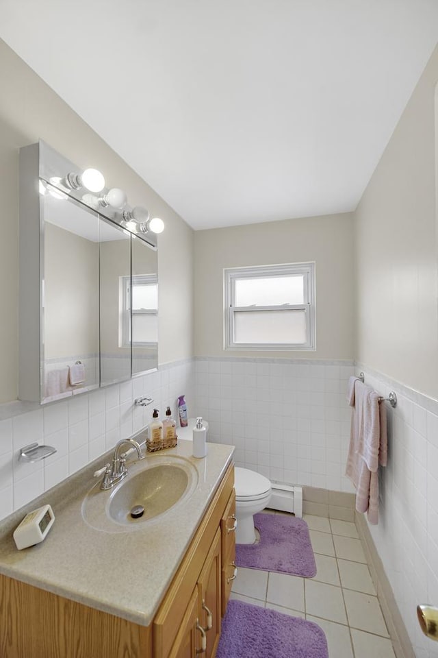 bathroom featuring tile patterned flooring, toilet, a baseboard heating unit, vanity, and tile walls