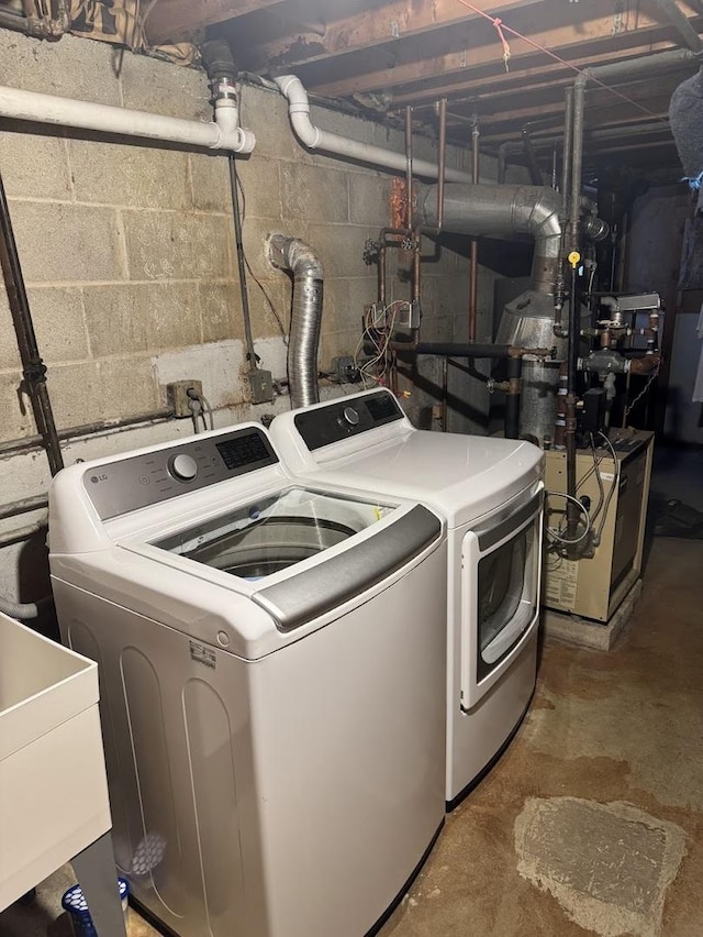 laundry room featuring laundry area, a heating unit, a sink, and washing machine and clothes dryer