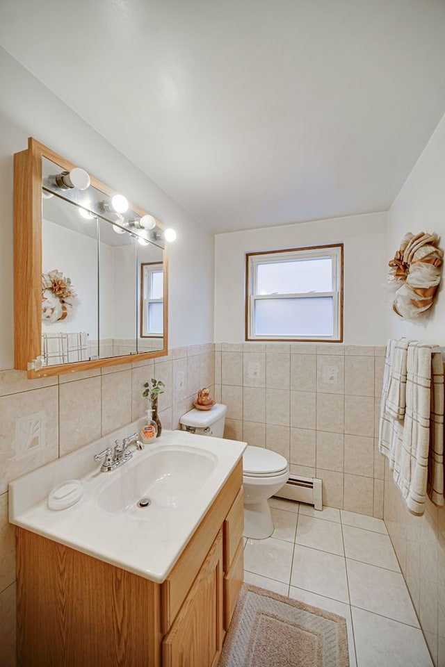 bathroom with toilet, a baseboard heating unit, vanity, tile walls, and tile patterned floors