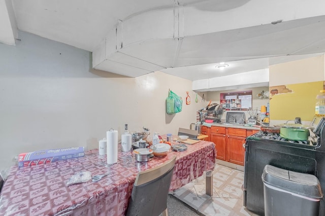 kitchen with brown cabinetry, light countertops, light floors, and gas range oven