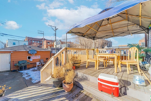 wooden deck with grilling area, outdoor dining area, and an outbuilding