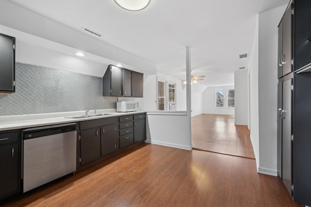 kitchen with white microwave, wood finished floors, a sink, a ceiling fan, and stainless steel dishwasher