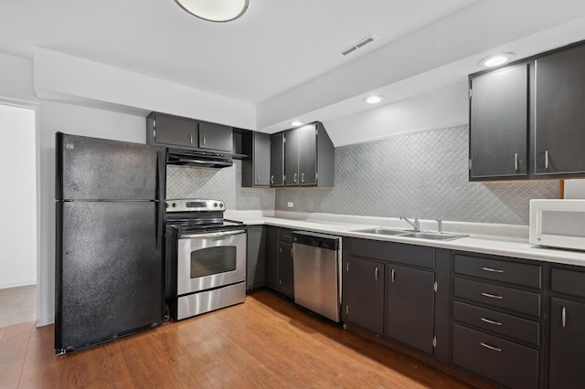 kitchen featuring stainless steel appliances, visible vents, light wood-style flooring, decorative backsplash, and a sink