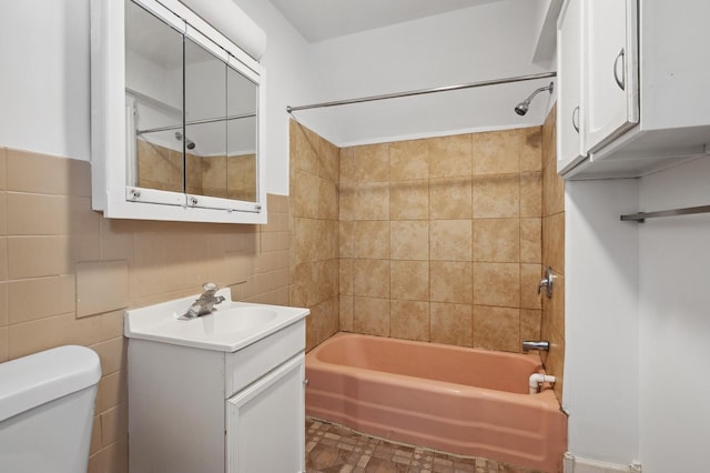 bathroom featuring  shower combination, vanity, toilet, and tile walls