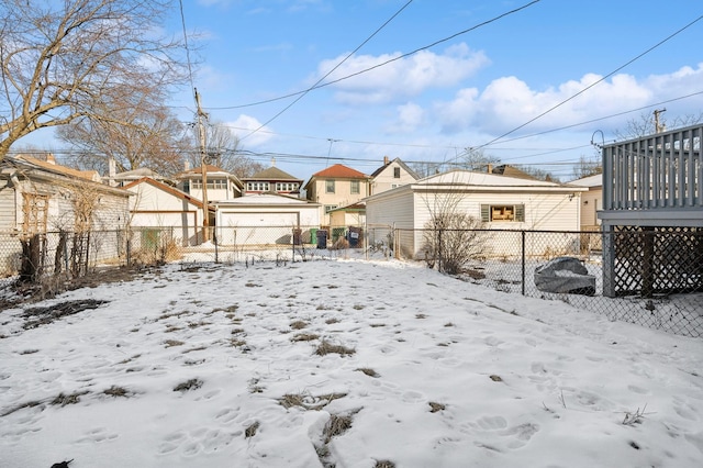 snowy yard with a detached garage, a fenced backyard, and a residential view