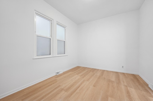 empty room featuring light wood-style flooring, visible vents, and baseboards