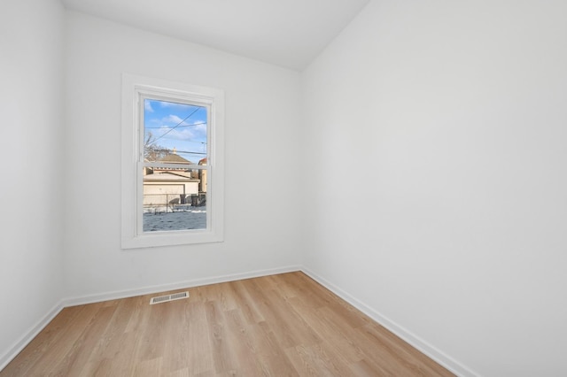 empty room featuring light wood finished floors, baseboards, and visible vents