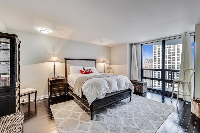 bedroom featuring baseboards, dark wood-type flooring, and floor to ceiling windows