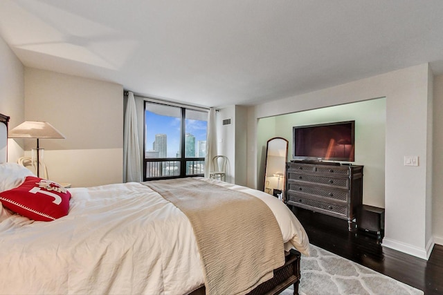 bedroom with visible vents, floor to ceiling windows, baseboards, and wood finished floors