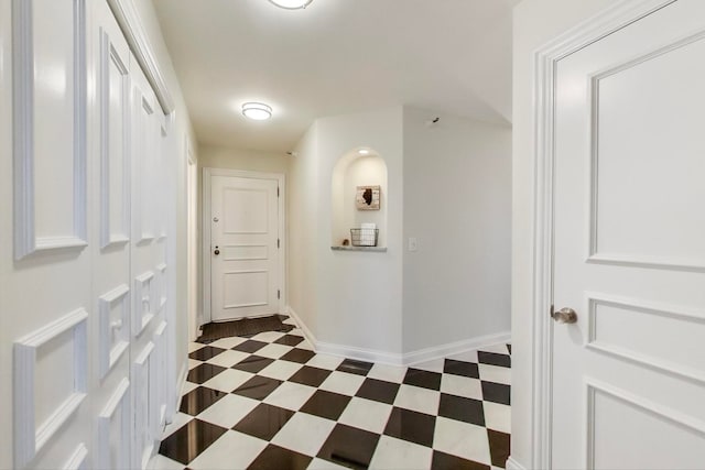 hallway featuring dark floors and baseboards