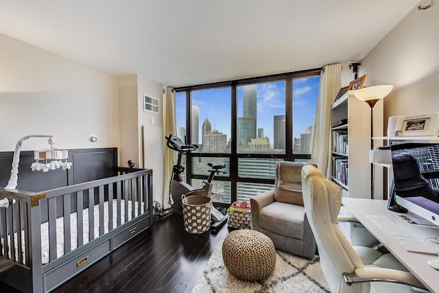 bedroom with floor to ceiling windows, visible vents, a city view, and wood finished floors